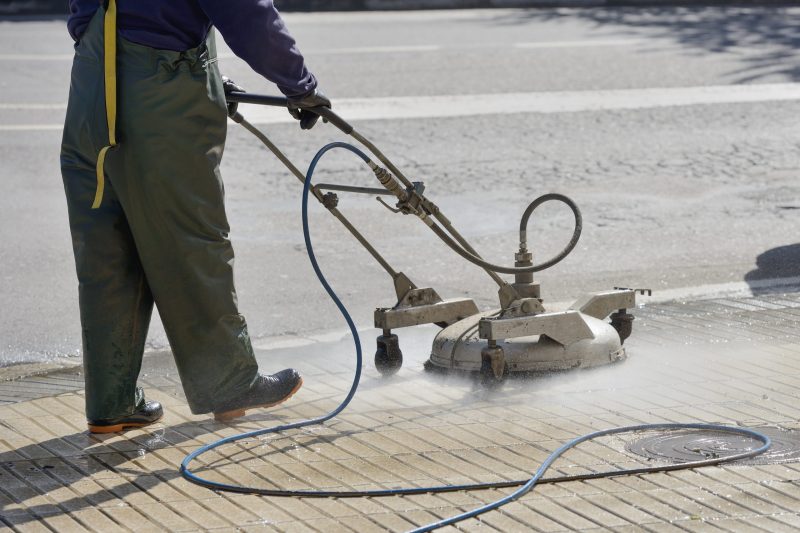 Man pressure washing sidewalk